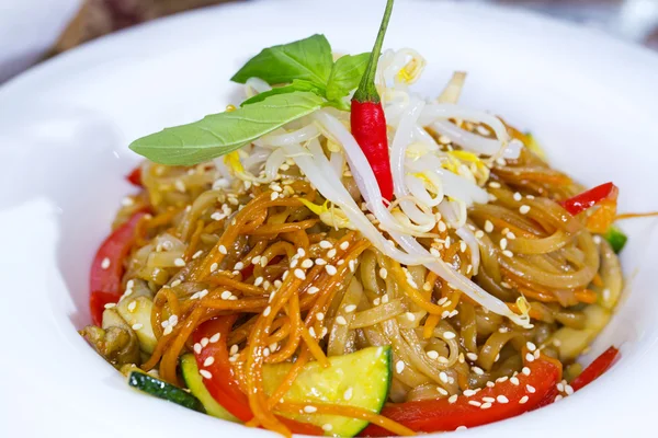 Rice spaghetti with vegetables on a white plate in a restaurant — Stock Photo, Image