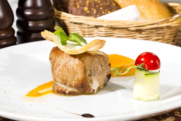 Baked meat with sauce and garnish on a plate in a restaurant — Stock Photo, Image