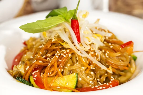 Esparguete de arroz com legumes em um prato branco em um restaurante — Fotografia de Stock