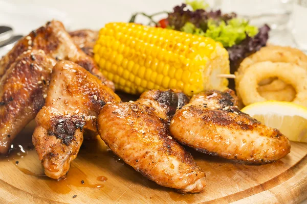 Chicken wings are grilled on a wooden platter — Stock Photo, Image