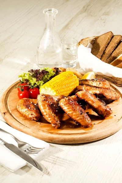 Chicken wings are grilled on a wooden platter — Stock Photo, Image