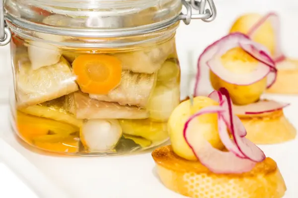 Ingelegde haringen in een glazen pot met aardappel canapeetjes — Stockfoto