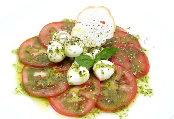 Tomatoes with cheese sauce poured on a white plate in a restaurant — Stock Photo, Image