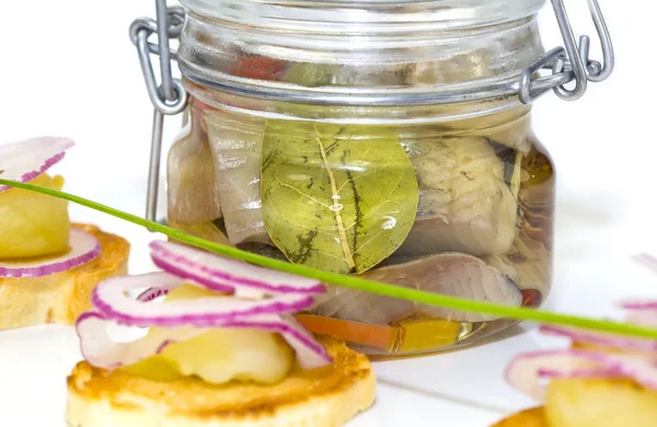 Ingelegde haringen in een glazen pot met aardappel canapeetjes — Stockfoto