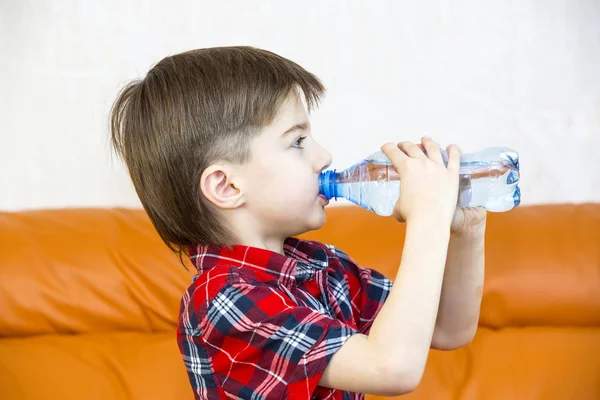 Jongen drinkt water uit een plastic fles — Stockfoto