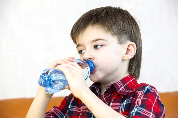 Jongen drinkt water uit een plastic fles — Stockfoto