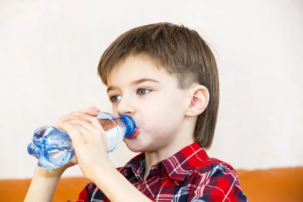 Jongen drinkt water uit een plastic fles — Stockfoto