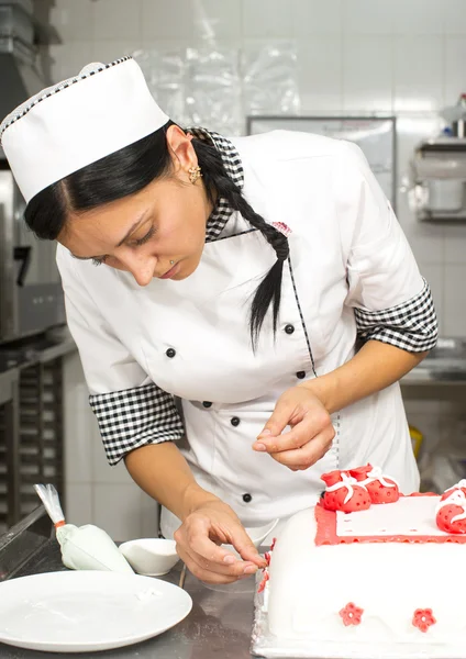 Chef de pastelaria decora um bolo — Fotografia de Stock