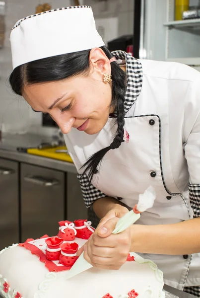 Chef de pastelaria decora um bolo — Fotografia de Stock