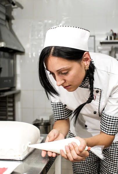 Chef de pastelaria decora um bolo — Fotografia de Stock