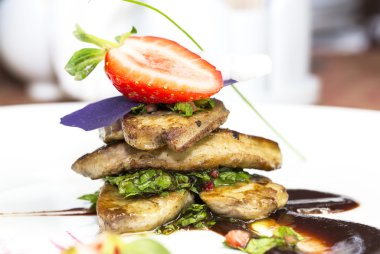 kızartma kaz ciğeri, yeşillik ve çilek ile süslüdür.