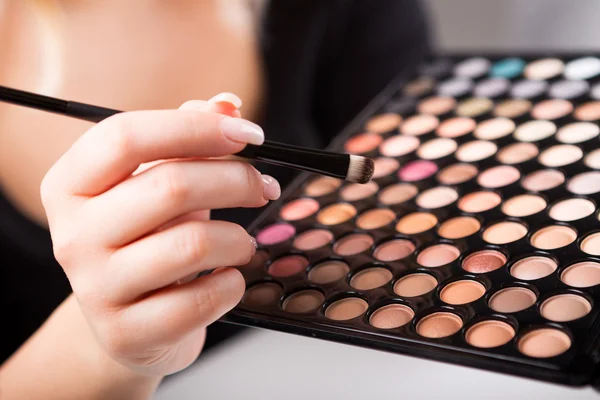 Female hand with makeup brush and paints — Stock Photo, Image