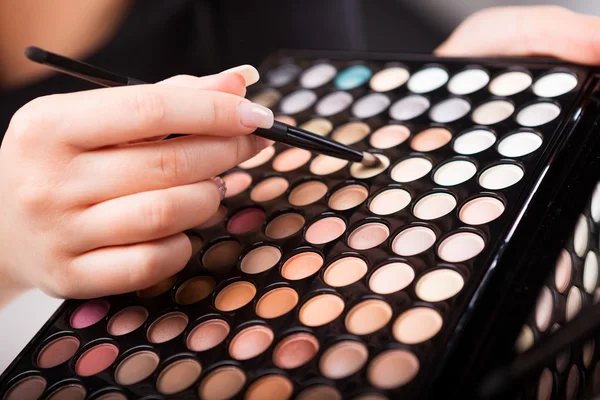 Female hand with makeup brush and paints — Stock Photo, Image