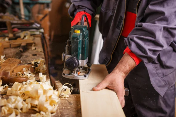 Carpinteiro no trabalho com marcenaria plaina elétrica — Fotografia de Stock