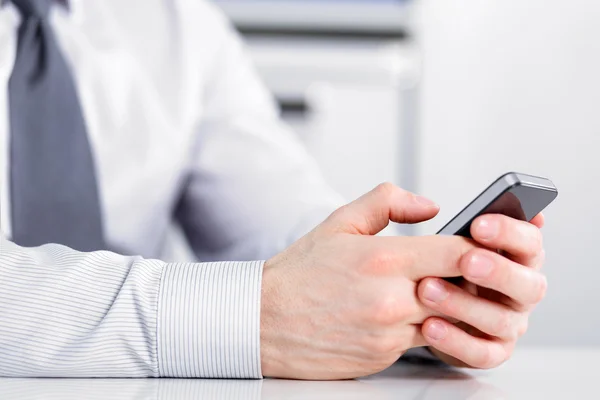 Mannenhand houden van een mobiele telefoon en schrijven — Stockfoto