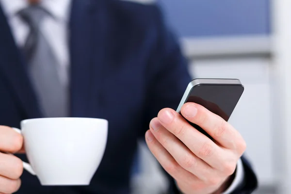 Επιχειρηματίας, κρατώντας ένα κινητό τηλέφωνο και καφέ — Φωτογραφία Αρχείου