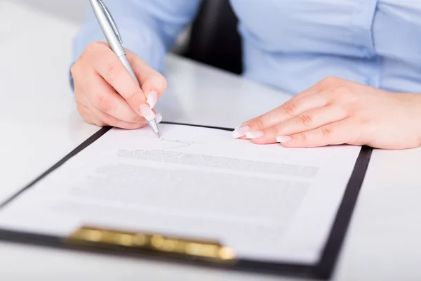 Young woman signs a contract — Stock Photo, Image