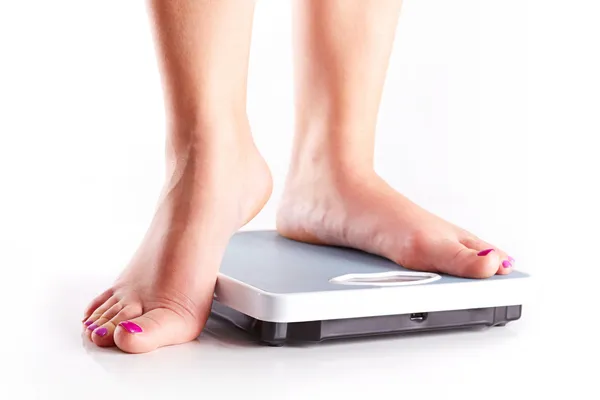 A pair of female feet on a bathroom scale — Stock Photo, Image