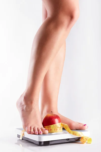 A pair of female feet standing on a bathroom scale with red appl — Stock Photo, Image