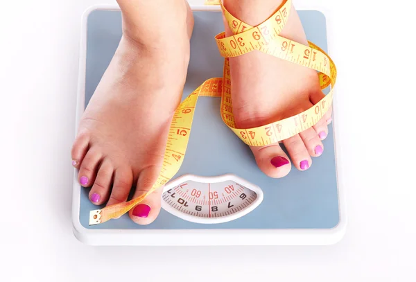 A pair of female feet standing on a bathroom scale — Stock Photo, Image