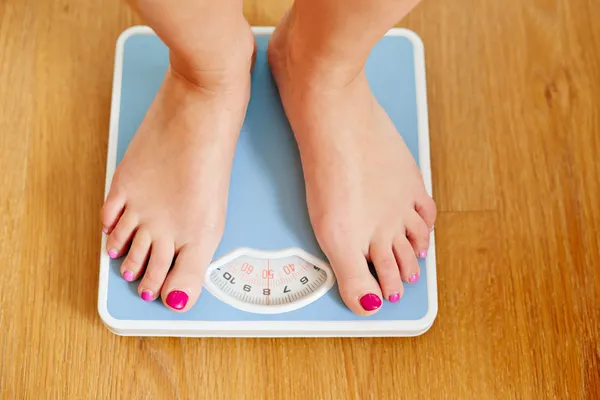 Vrouwelijke blote voeten met gewicht schaal — Stockfoto