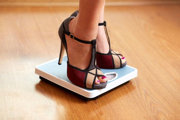 Female feet in color stilettos with weight scale