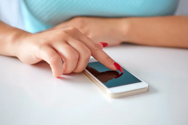 Mobilní telefon na bílý stůl a mladá žena — Stock fotografie