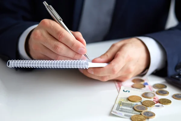 Geschäftsmann hält einen Stift in der Hand und schreibt auf Notizblock — Stockfoto