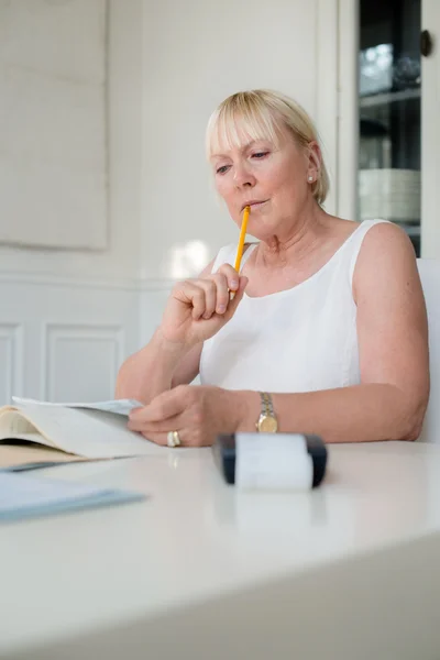 Reife Frau prüft Rechnungen und erledigt Haushalt zu Hause — Stockfoto