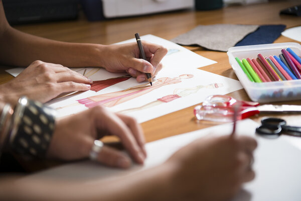 дизайнеры женской одежды, рисующие новое платье в студии
