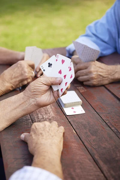 Активные пенсионеры, группа старых друзей, играющих в карты в парке — стоковое фото