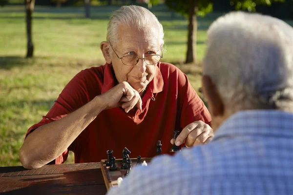 Активный пенсионер, двое старших играют в шахматы в парке — стоковое фото