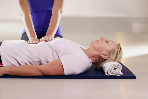 Joven terapeuta haciendo terapia de reiki a una mujer mayor — Foto de Stock