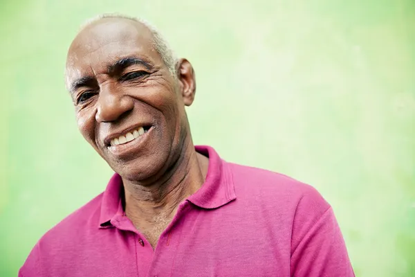 Retrato de homem negro idoso olhando e sorrindo para a câmera — Fotografia de Stock