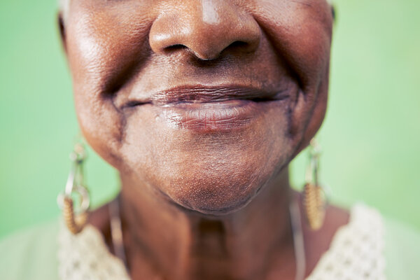 Closeup of old woman mouth against green background