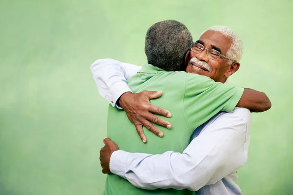 Старі друзі, двоє старших афроамериканських чоловіків зустрічаються і обіймаються Стокове Зображення