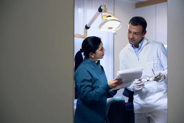 Dentiste et assistant vérifiant les documents en cabinet dentaire — Photo