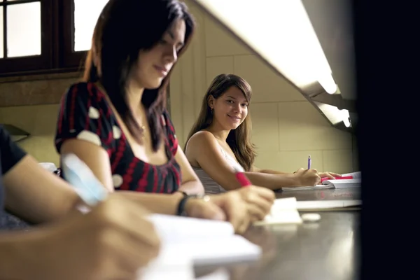 Šťastné studentka se usmívá na kameru v college library — Stock fotografie