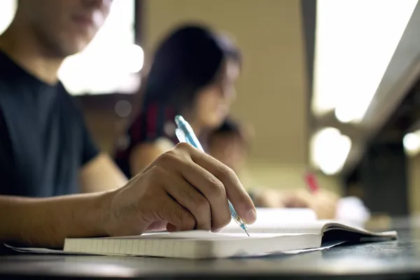 Jovem fazendo lição de casa e estudando na biblioteca da faculdade Fotos De Bancos De Imagens Sem Royalties