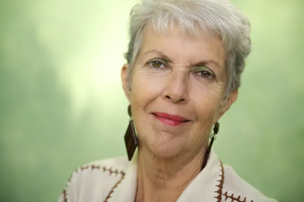 Portrait of old caucasian lady looking and smiling at camera — Stok fotoğraf