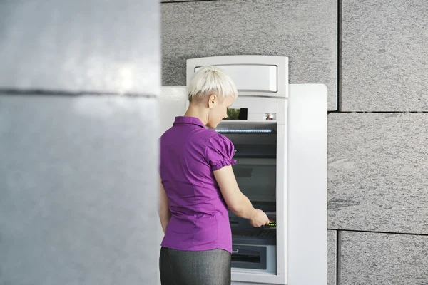 Молодая женщина снимает деньги с карты в банкомате — стоковое фото