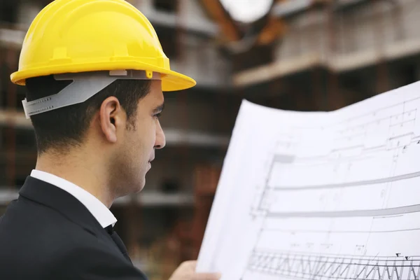 Architect in construction site looking at building plans — Stock Photo, Image