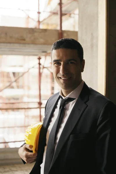 Ingeniero con casco en obra sonriendo a cámara, por — Foto de Stock