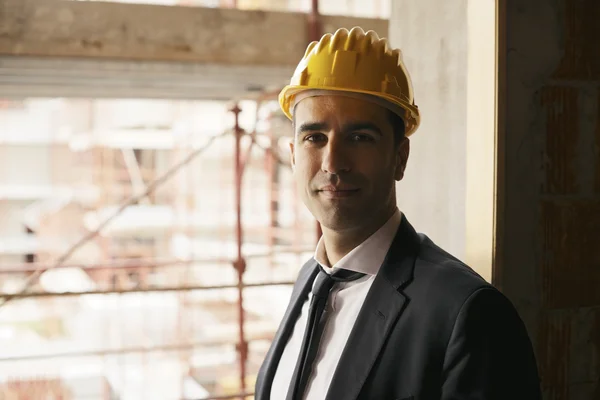 Inżynier z kaskiem w budowie uśmiecha się do kamery, por — Zdjęcie stockowe