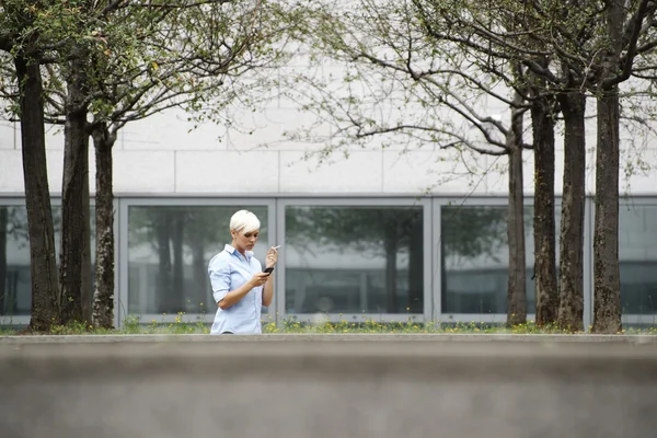 Mulher de negócios fumando cigarro e digitando sms no telefone — Fotografia de Stock