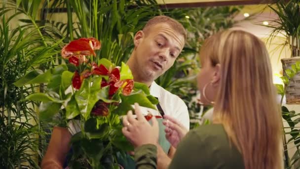Мужчина в цветочном магазине продает завод клиенту — стоковое видео
