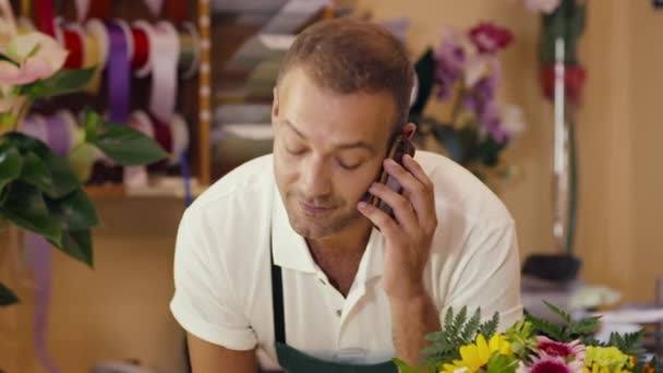 Флорист беседует с клиентом по телефону и продает цветы — стоковое видео