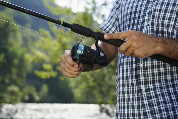 Fisherman standing near river and holding fishing rod — Stock Photo, Image