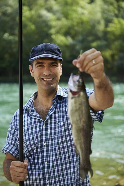 Homem pescando no rio e mostrando peixe para a câmera — Fotografia de Stock