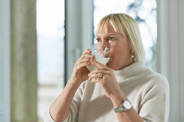 Portrait of senior woman having breakfast with milk — Stock Photo, Image